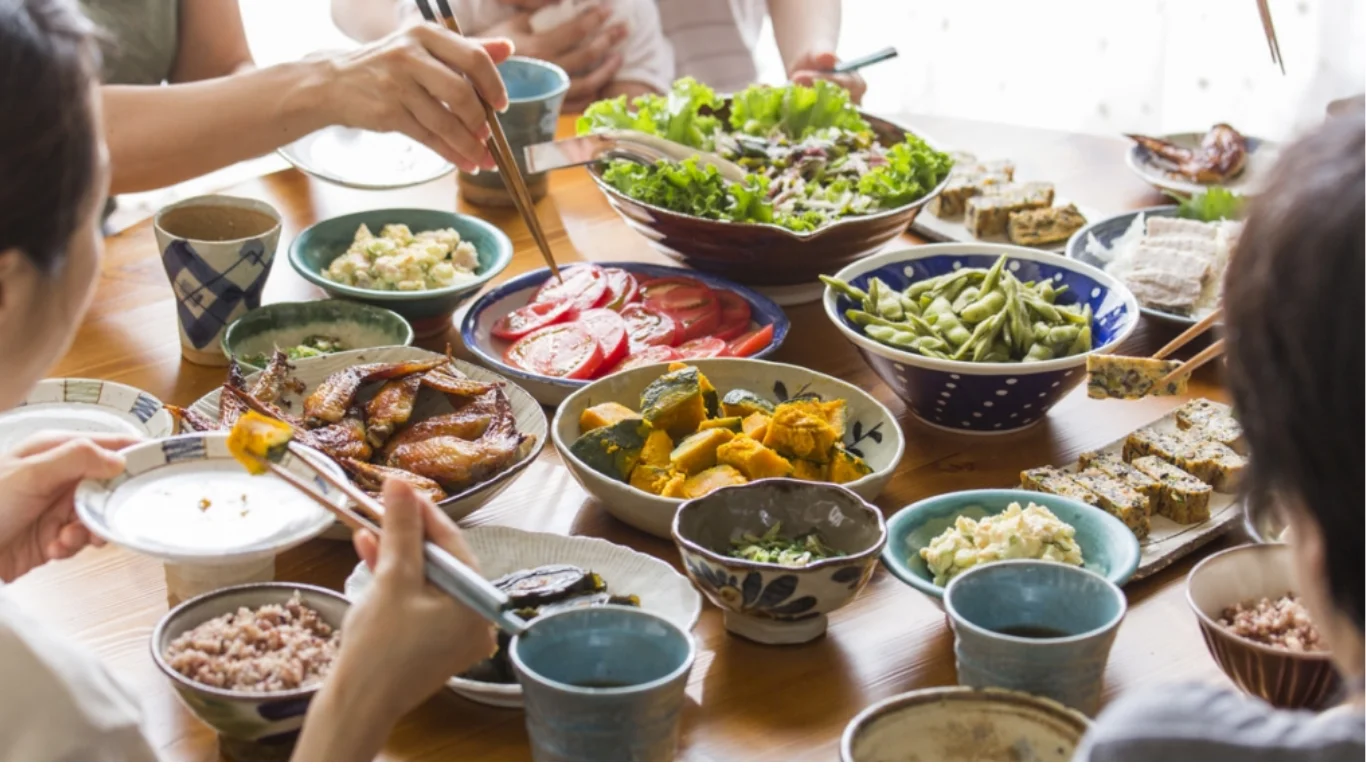 家族が食卓を囲み色とりどりの手料理を取り分ける様子