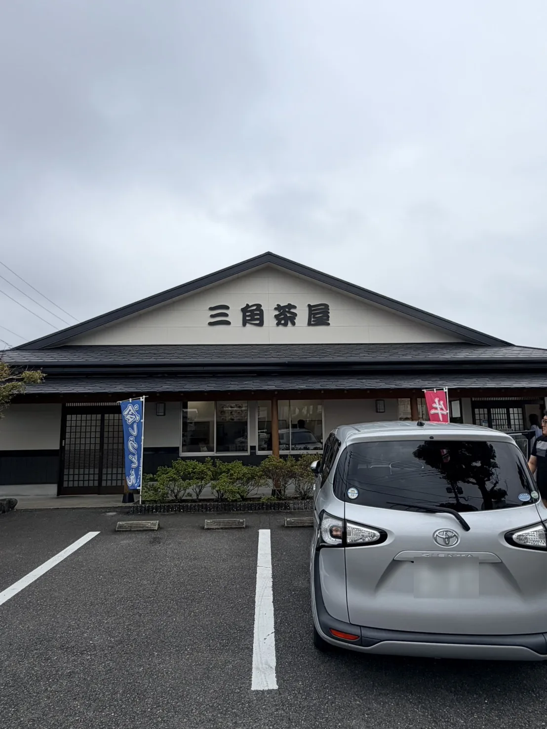 三角茶屋 豊吉うどん本店の外観。曇り空の下、切妻の三角屋根に「三角茶屋」の切り文字が掲げられている